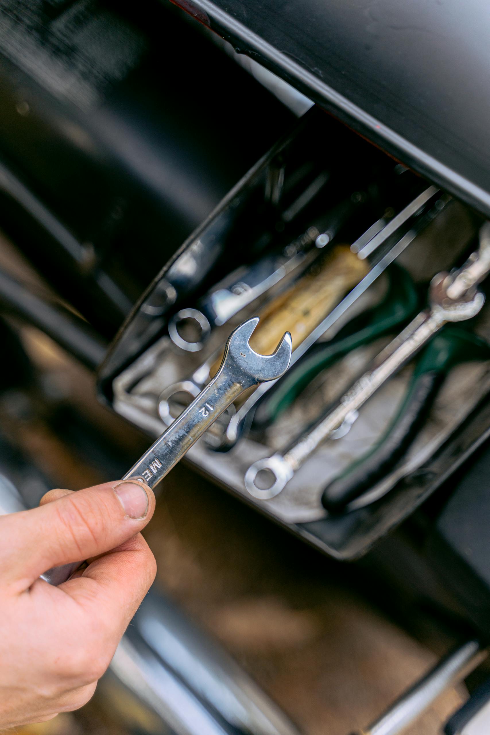 Trades SEO - Close-up of a hand holding a metal wrench in front of an open tool box.